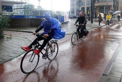 Gente en bicicleta bajo la lluvia