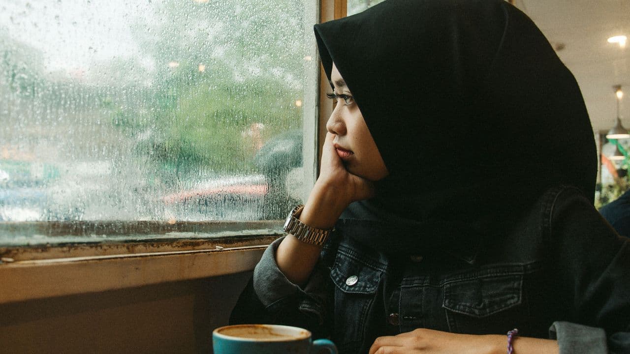 Mujer con hijab mirando por una ventana