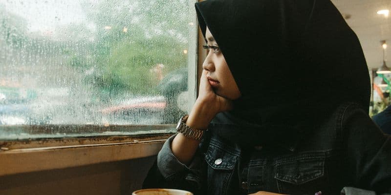 Mujer con hijab mirando por una ventana