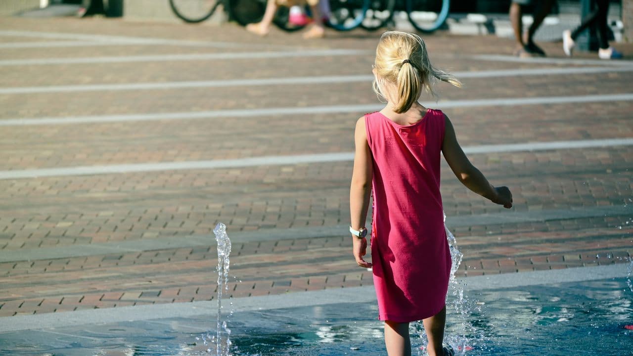 Niña jugando en una fuente de agua