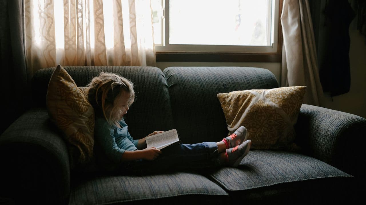 Niña leyendo en un sofá