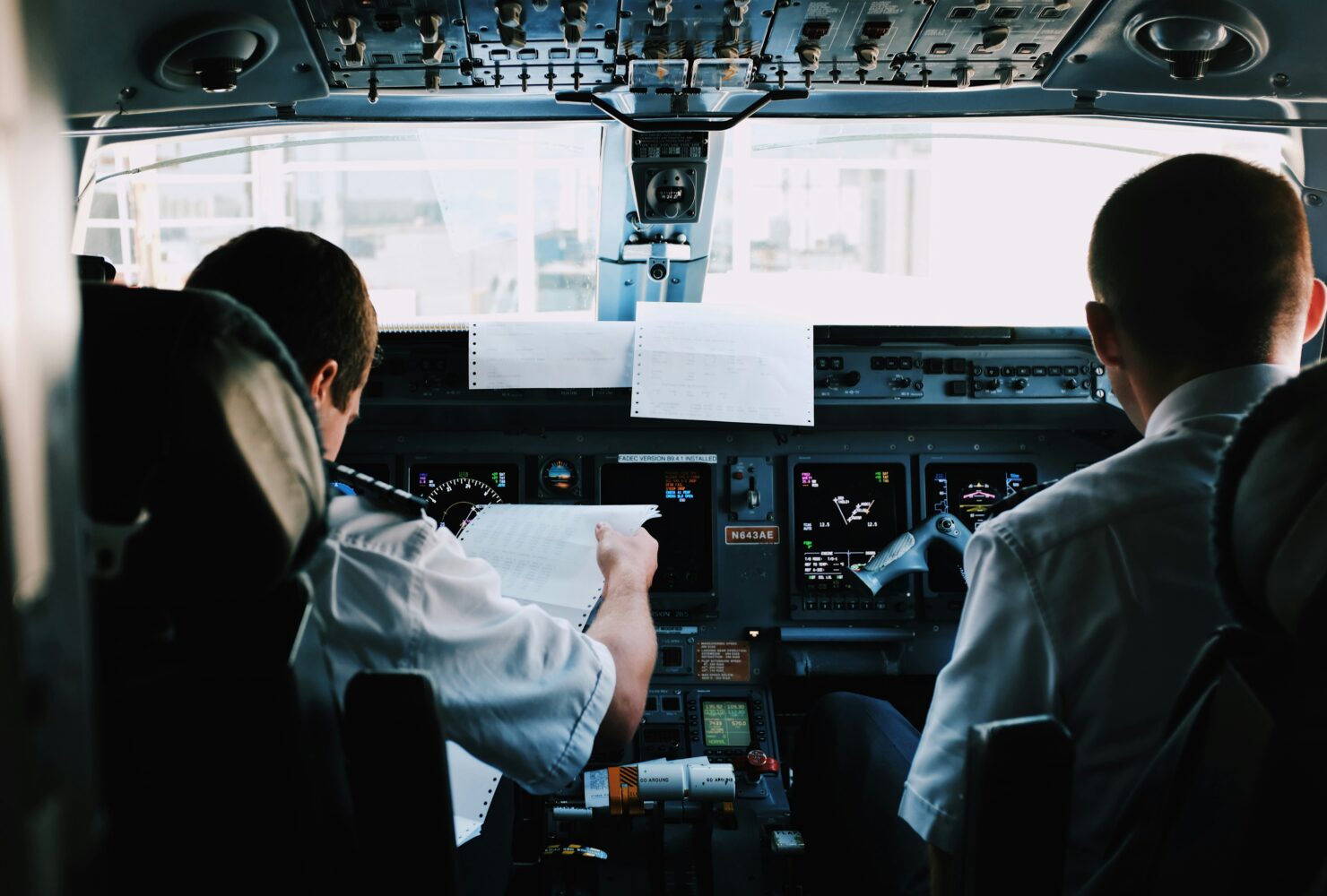 Pilotos en uniforme discutiendo frente a una terminal del aeropuerto de Schiphol sobre el cierre nocturno del aeropuerto