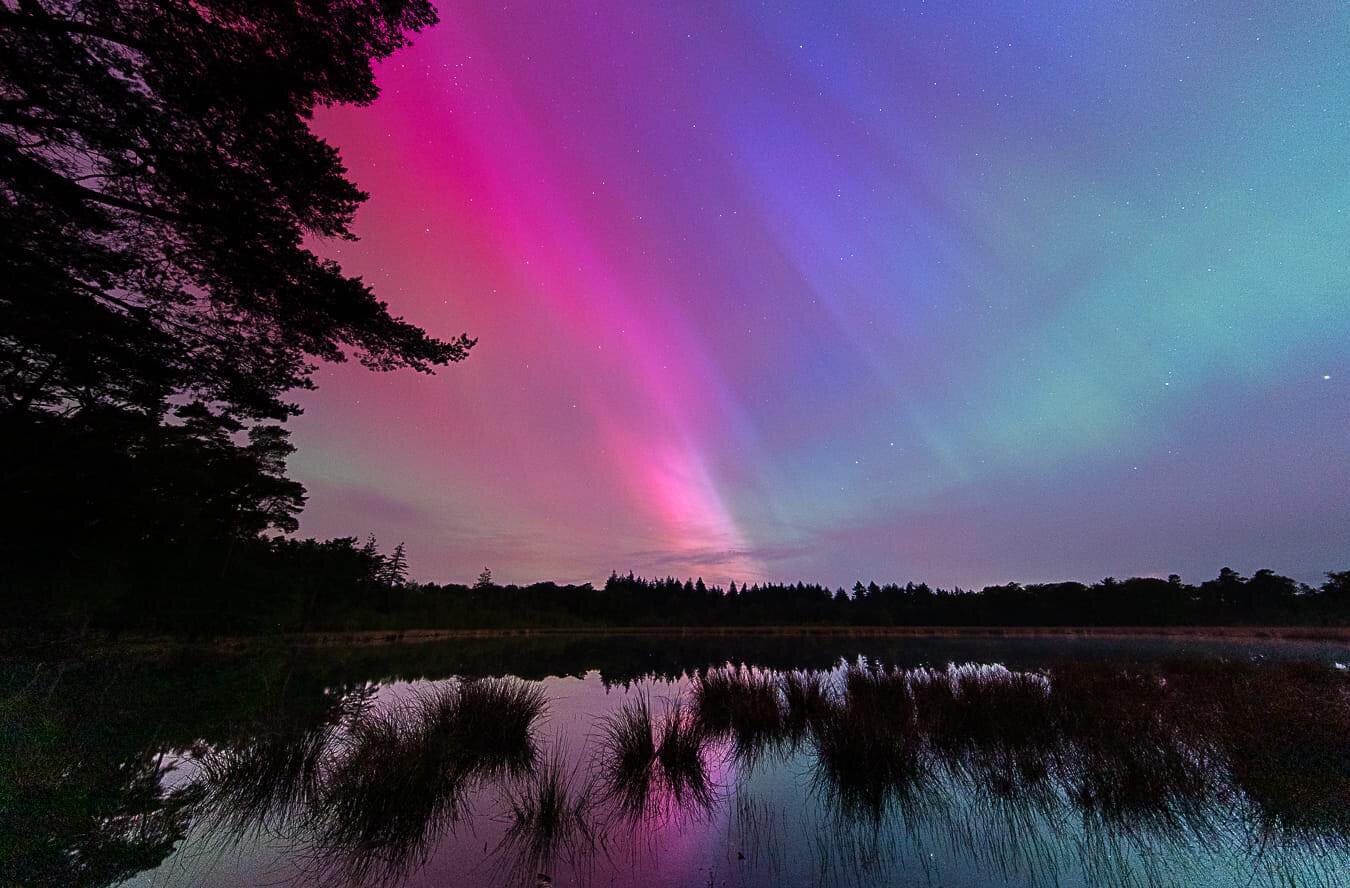 Imagen de la aurora boreal visible en los Países Bajos, iluminando el cielo nocturno con colores vibrantes