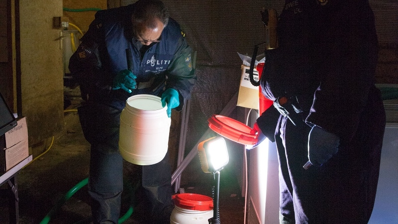 Policía holandesa desmantelando un laboratorio de drogas con equipo especializado, mostrando el incremento en la producción de heroína y drogas sintéticas en 2023.