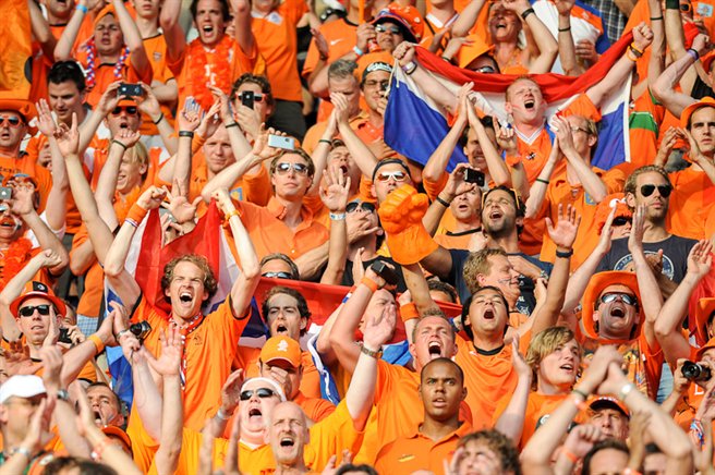 Aficionados holandeses de naranja con banderas y decoraciones, dirigiéndose hacia Hamburgo para el Campeonato de Europa.